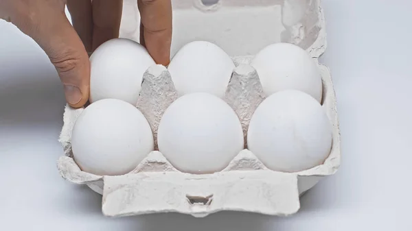 Partial view of man taking fresh egg from package on white surface — Stock Photo
