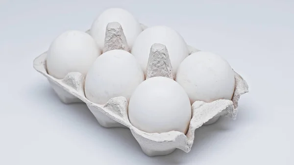 Seis ovos de galinha em pacote de papelão na superfície branca — Fotografia de Stock