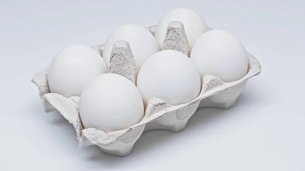 Seis ovos de galinha em pacote de papelão na superfície branca — Fotografia de Stock