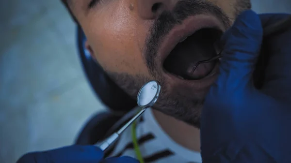 Visão recortada de dentista examinando dentes de paciente com instrumentos odontológicos — Fotografia de Stock