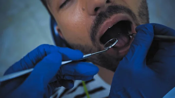 Visão parcial do estomatologista examinando os dentes do homem com instrumentos odontológicos — Fotografia de Stock