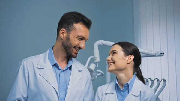 Happy dentists in white coats looking at each other in clinic — Stock Photo