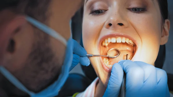 Stomatologist na máscara médica que examina dentes da mulher, foreground borrado — Fotografia de Stock