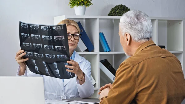 Médico que muestra radiografía al paciente durante la consulta en el hospital - foto de stock