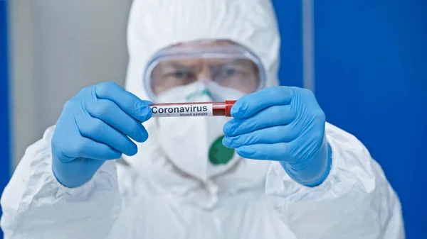 Вчений у костюмі з туманом, що показує тест на коронавірус, розмитий фон — стокове фото