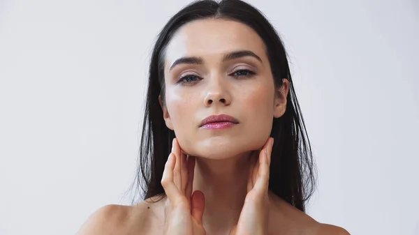 Brunette woman touching perfect skin while looking at camera isolated on grey — Stock Photo