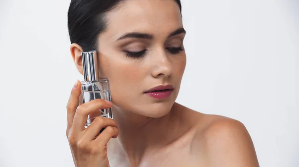 Brunette woman with naked shoulders holding perfume isolated on white — Stock Photo