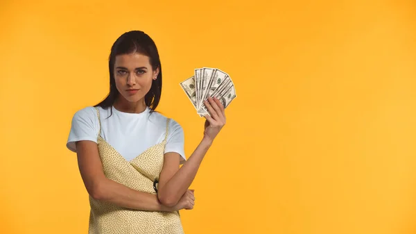 Молода жінка тримає доларові банкноти ізольовані на жовтому — стокове фото