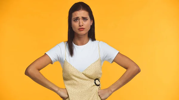 Donna scontenta in piedi con le mani sui fianchi isolato sul giallo — Foto stock