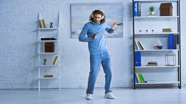 Ganzkörperansicht eines jungen Geschäftsmannes mit drahtlosen Kopfhörern, der im modernen Büro tanzt — Stockfoto