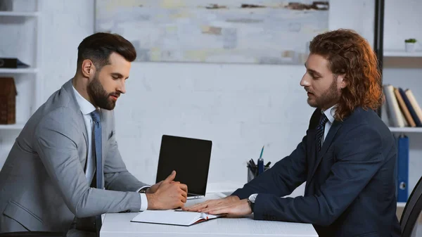 Junge Geschäftsleute in formeller Kleidung reden in der Nähe von Laptop im Büro — Stockfoto