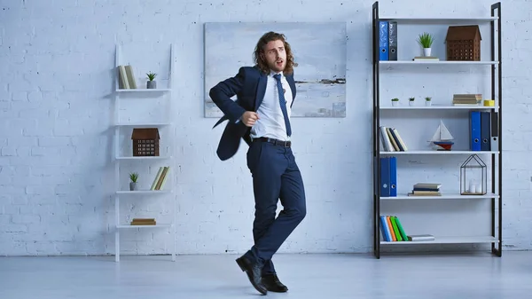Ganzkörperansicht des jungen Managers in formeller Kleidung, der im modernen Büro tanzt — Stockfoto
