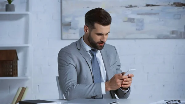 Businessman in formal wear chatting on mobile phone at workplace — Stock Photo