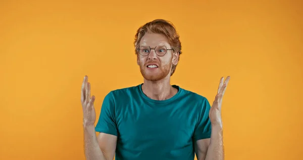 Angry redhead man in glasses gesturing isolated on yellow — Stock Photo