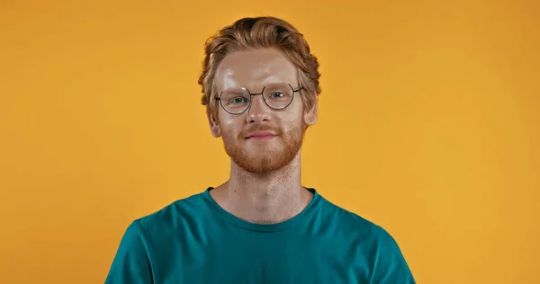 Positive redhead man in glasses looking at camera isolated on yellow — Stock Photo