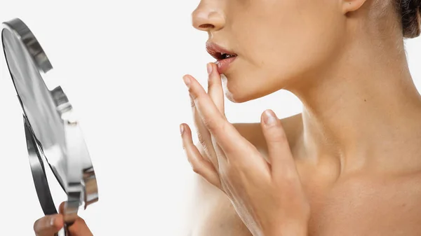 Vista ritagliata di donna con spalle nude applicando balsamo labbra e tenendo specchio isolato su bianco — Foto stock