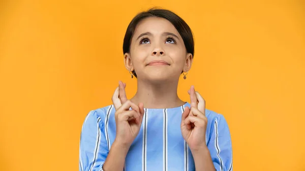 Preteen child with crossed fingers looking up isolated on yellow — Stock Photo