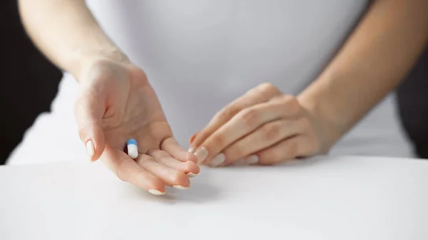 Vista recortada de la mujer embarazada sosteniendo píldora, fondo borroso - foto de stock