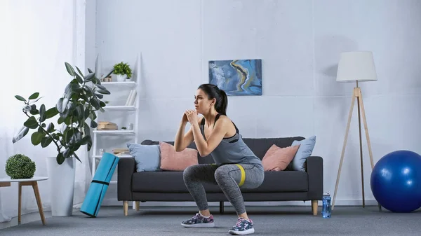 Young woman in sportswear exercising with resistance band at home — Stock Photo