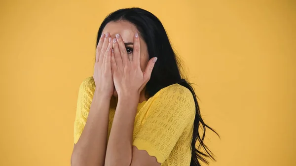 Mulher assustada cobrindo rosto com as mãos isoladas no amarelo — Fotografia de Stock