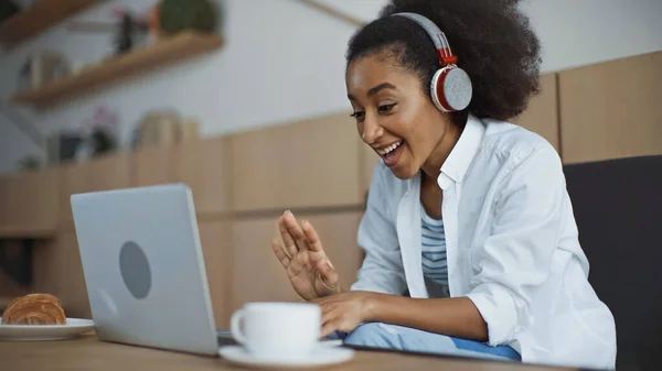 Felice donna d'affari africana americana in cuffie senza fili con video chat in caffè — Foto stock