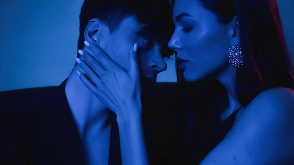 Seductive woman embracing man in blazer on blue — Stock Photo