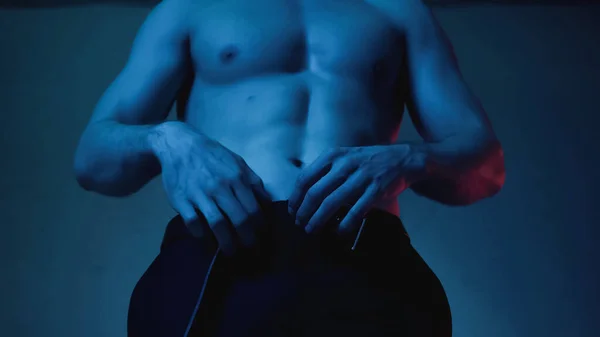 Corte vista de sexy e muscular homem despir no azul — Fotografia de Stock