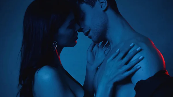 Side view of woman kissing shirtless boyfriend ton blue — Stock Photo