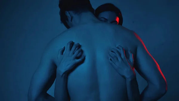 Brünette Frau kratzt dem hemdslosen Mann auf blauem Grund den Rücken — Stockfoto