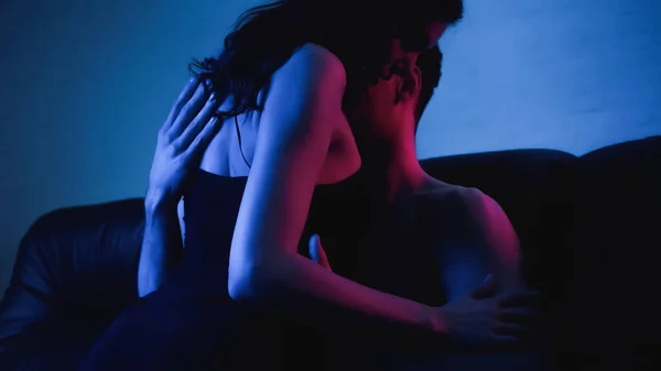 Brunetta donna in abito slip nero seduto su uomo muscolare su blu — Foto stock