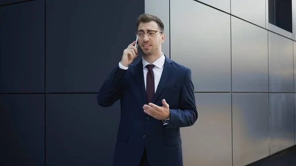 Hombre de negocios hablando por celular cerca del edificio - foto de stock