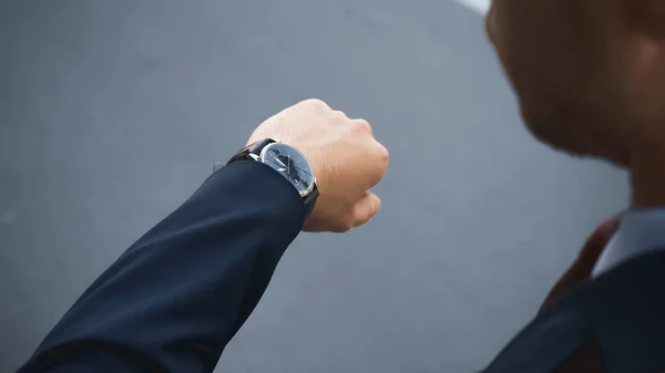 Vista ritagliata di uomo d'affari in abbigliamento formale guardando orologio da polso durante l'attesa fuori — Foto stock