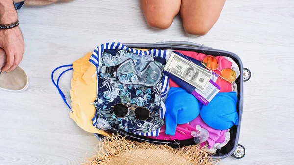 Visão parcial de homem e mulher perto da bagagem com roupas de verão, dinheiro, passaportes e bilhetes de viagem — Fotografia de Stock