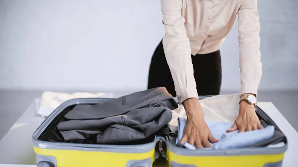 Vista cortada de empresária que embala roupas em bagagem em casa — Fotografia de Stock