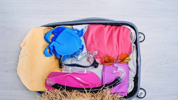 Vista superior da mala embalada com roupas de verão em casa — Fotografia de Stock