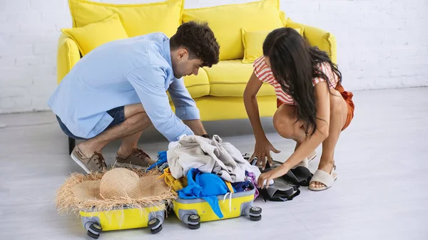 Hombre y mujer embalaje maleta amarilla en la sala de estar - foto de stock