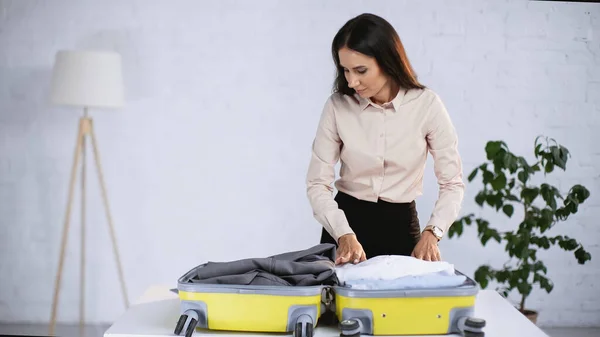 Brunette femme d'affaires emballage jaune valise à la maison — Photo de stock