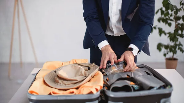 Cropped view of businessman in suit packing luggage — Stock Photo