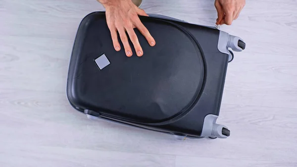 Top view of man zipping black luggage — Stock Photo