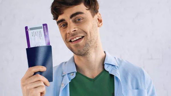 Homem feliz em camisa azul segurando passaporte com bilhete de ar — Fotografia de Stock