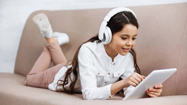 Preteen girl in headphones using digital tablet at home — Stock Photo