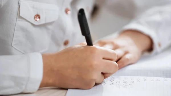 Cropped view of kid writing on notebook on blurred foreground — Stock Photo