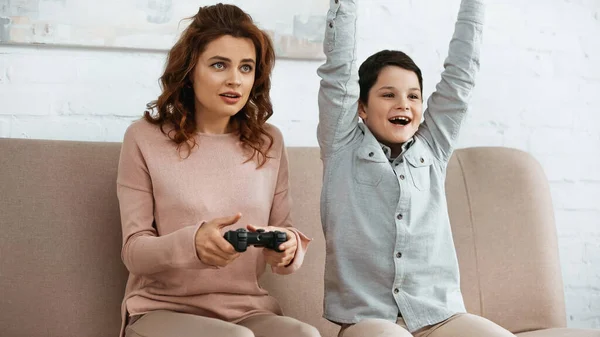 KYIV, UKRAINE -  APRIL 15, 2019: Woman playing video game near cheerful son at home — Stock Photo