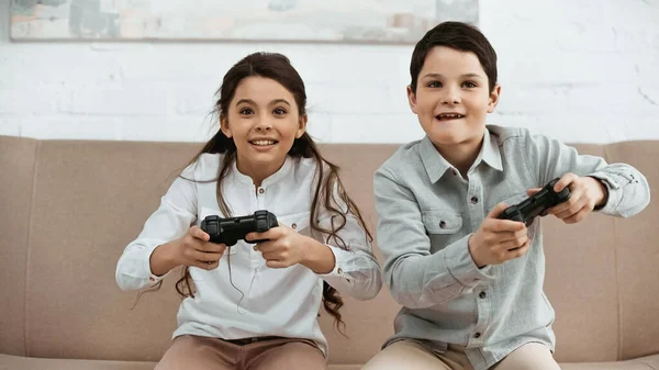 KYIV, UKRAINE -  APRIL 15, 2019: Positive kids playing video game in living room — Stock Photo