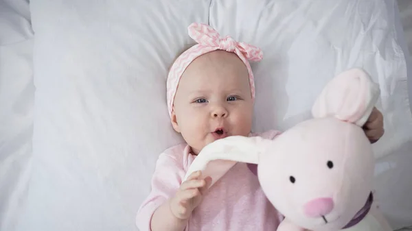 Vista superior de bebé niña sosteniendo juguete suave - foto de stock
