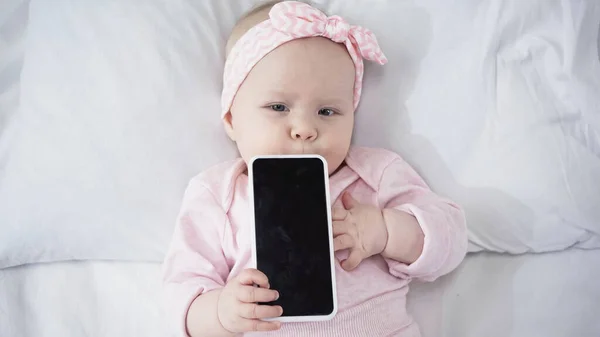 Top view of infant baby holding smartphone with blank screen — Stock Photo