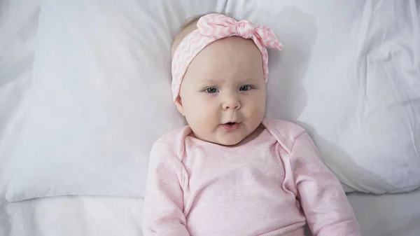 Vista superior do bebê infantil deitado na cama e olhando para a câmera — Fotografia de Stock