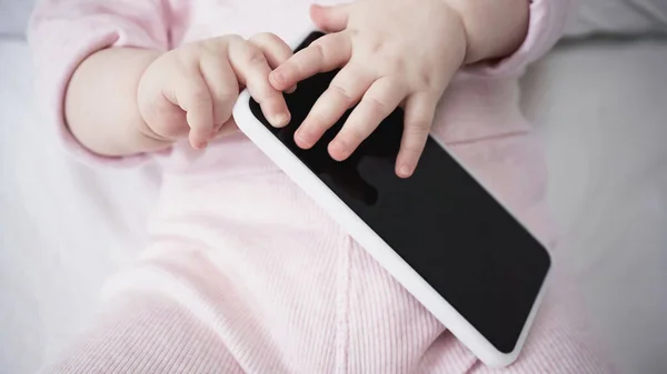 Vista cortada de menina infantil segurando smartphone com tela em branco — Fotografia de Stock