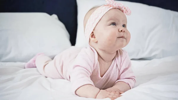 Bebê menina deitada na cama e olhando para cima — Fotografia de Stock