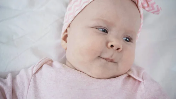 Vista dall'alto della bambina che distoglie lo sguardo mentre si trova a letto — Foto stock